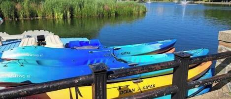 A row of blue and yellow kayaks docked at a pier with a cityscape in the background.