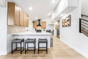 A modern kitchen with a large island, wooden cabinets, and a stainless steel refrigerator. - LUX 5BR | 2 Master BR | 2 Living Rooms |Pool & Spa (Las Vegas)