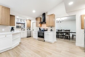 Una cocina moderna con armarios blancos, una isla central y un comedor con mesa y sillas.