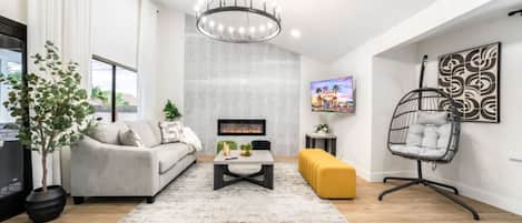 Una sala moderna con un sofá, una mesa de centro y un sillón colgante.