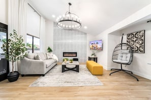 Un salon moderne avec un canapé, une table basse et un fauteuil suspendu.