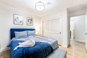 Ein Schlafzimmer mit einem großen Bett, einem blauen Kopfteil, einer Schwan-Dekoration und einer Tür mit Klappläden.
