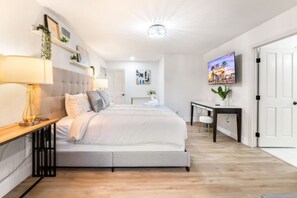 A modern bedroom with a bed, bedside table, lamp, and a TV on the wall. - LUX 5BR | 2 Master BR | 2 Living Rooms |Pool & Spa (Las Vegas)