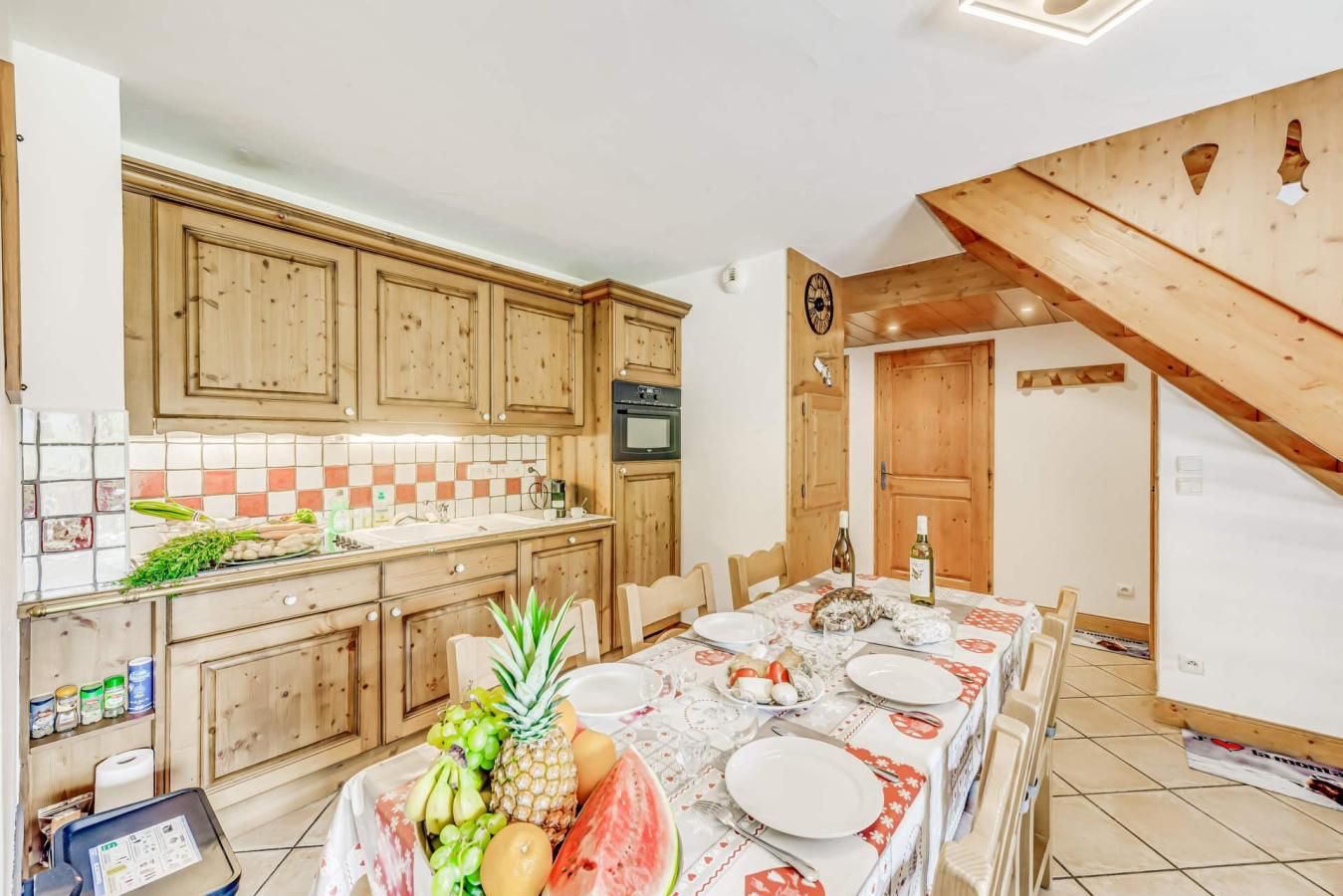 Eine Küche mit Holzschränken, einer gefliesten Spritzschutzwand und einem Essbereich mit Tisch für vier Personen.