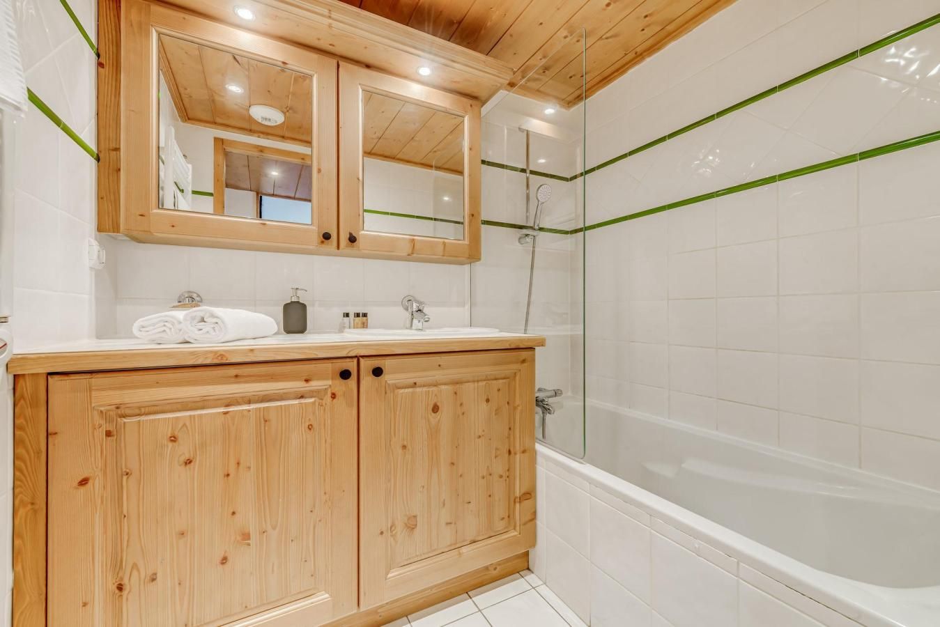 A wooden vanity with a mirror, a sink, and a shower area with a glass door.