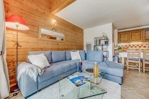 A cozy living room with a blue sofa, a glass coffee table, and a red lamp. - View valley/mountain, fitness, swimming pool, sauna, hammam, terrace, parking, tv, 76m² (Champagny-en-Vanoise)