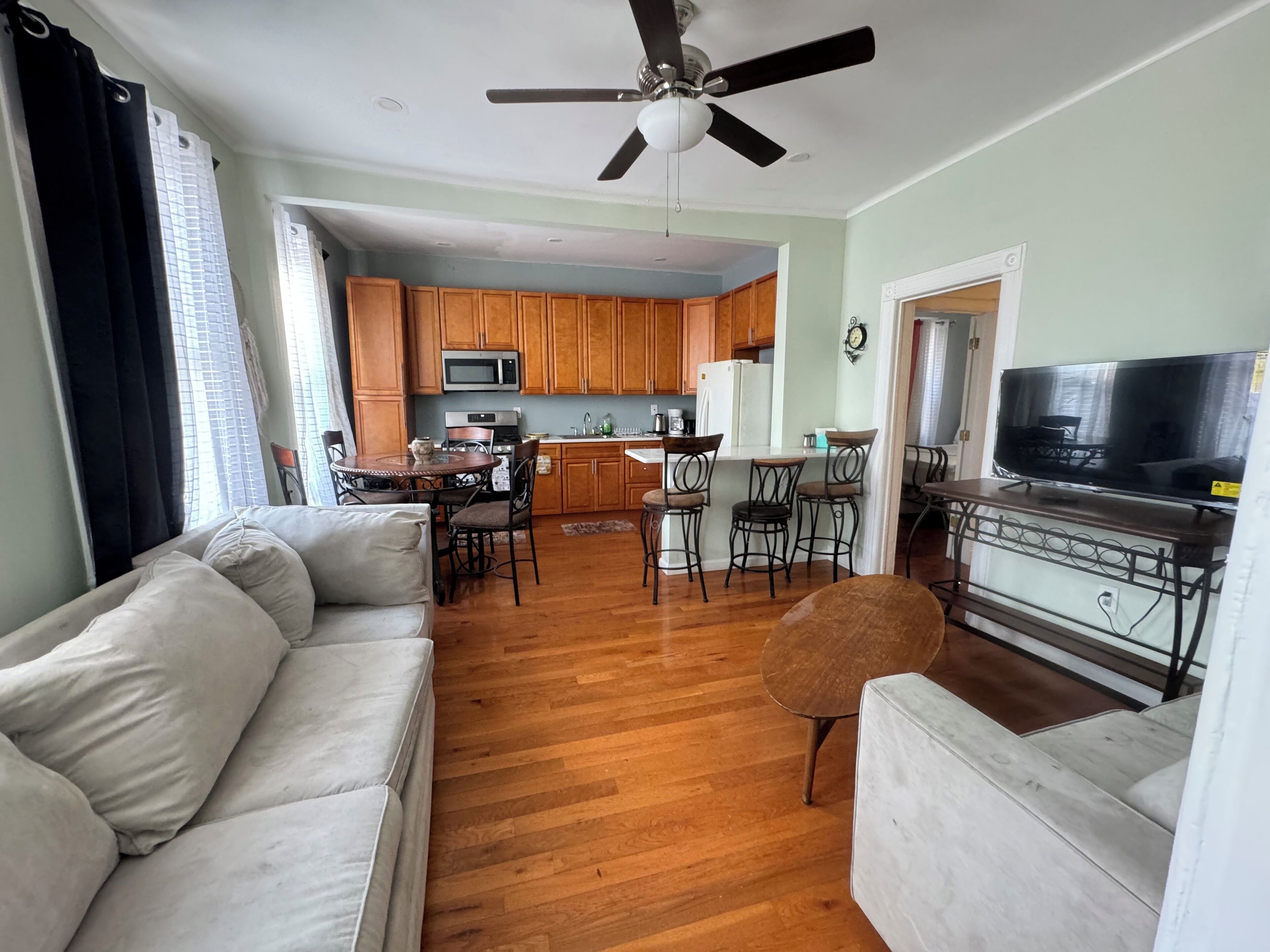 A living room with a sofa, a TV, and a dining area with chairs and a table.