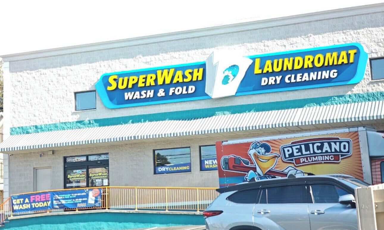 A building with a sign for SuperWash and laundromat services, and a Pelicano Plumbing advertisement.