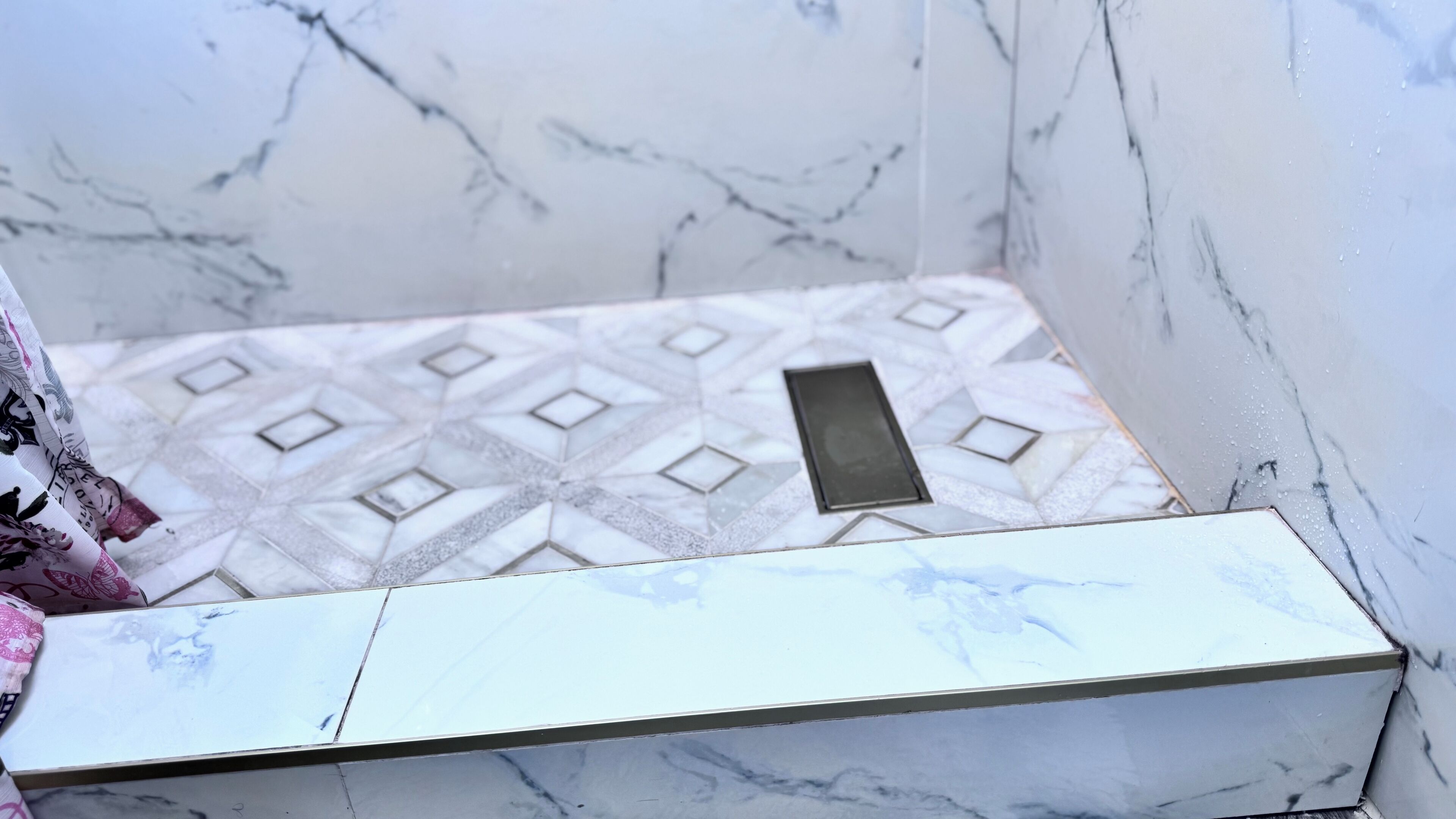 A bathroom with a marble floor, a white sink, and a mirror.