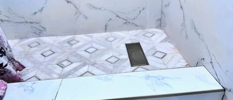 A bathroom with a marble floor, a white sink, and a mirror.