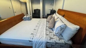 A double bed with patterned bedding, a wooden headboard, and a bedside table with a lamp.