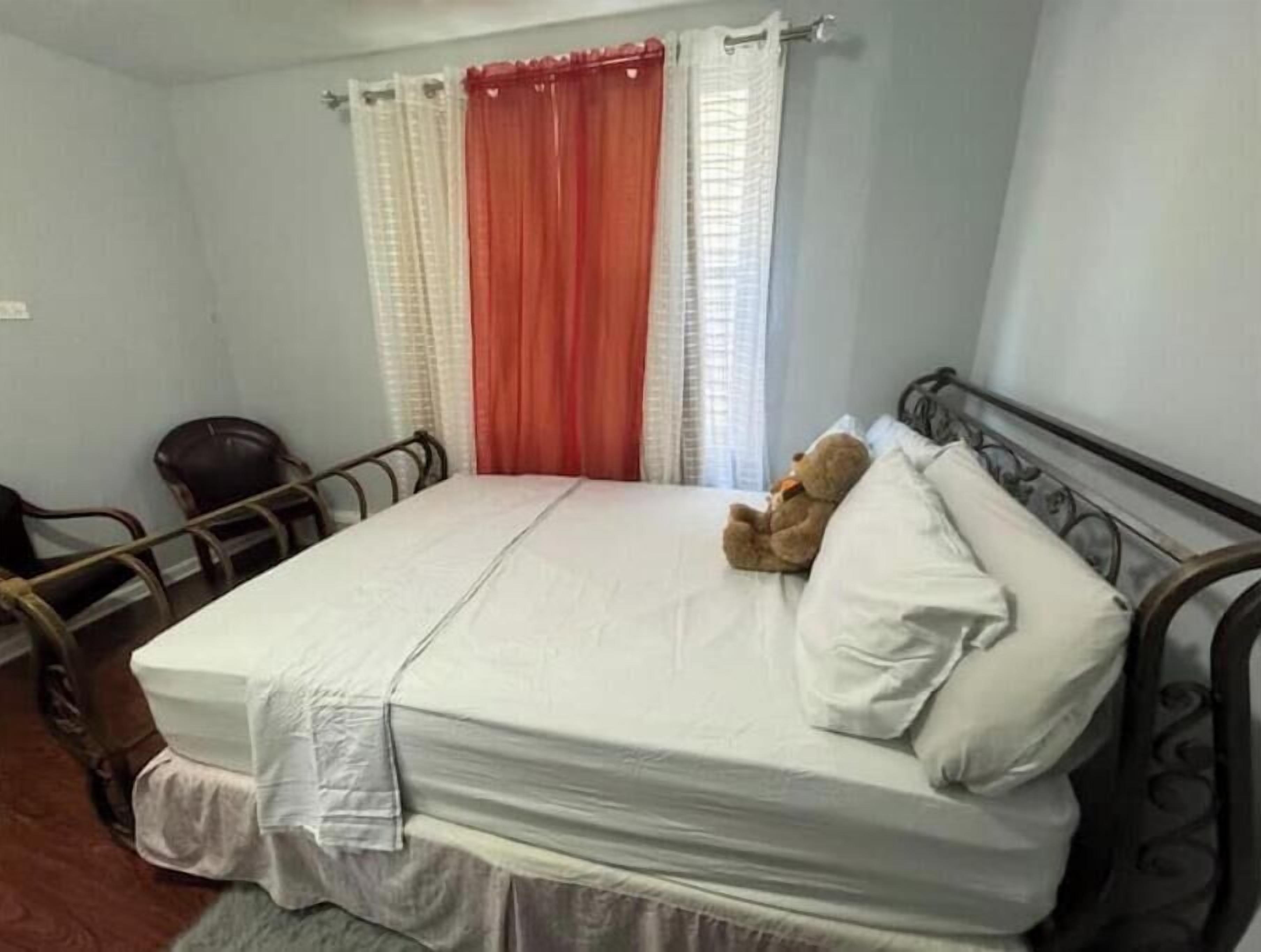 A single bed with a mattress, pillows, and a teddy bear.