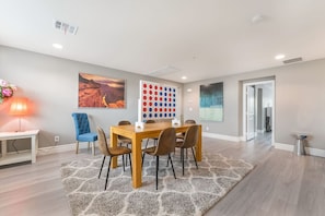 A modern dining room with a wooden table, chairs, a rug, and artwork on the walls.