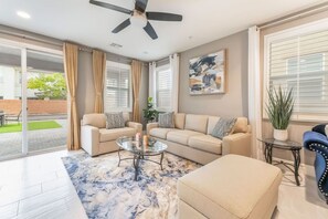Ein Wohnzimmer mit einer Sofagarnitur, einem Couchtisch, einem Deckenventilator und einem Bild an der Wand.