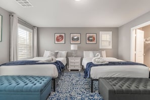 A hotel room with two beds, a nightstand, a lamp, and a patterned rug.