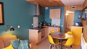 Une cuisine compacte dotée d’un îlot central, d  ’un coin repas avec des chaises jaunes et d’un coin cuisine avec des meubles en bois.
