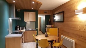 Une cuisine compacte avec des meubles en bois, un évier et un coin repas comprenant une table ronde et des chaises jaunes.