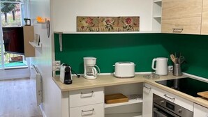 Una cucina moderna con mobili bianchi, una parete di sfondo verde e un forno integrato.