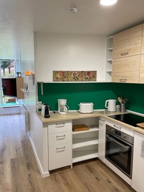 Eine moderne Küche mit weißen Schränken, einer grünen Spritzschutzwand und einem eingebauten Backofen.