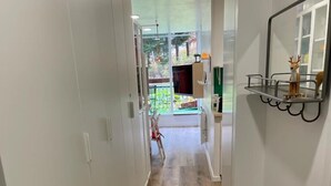 Un corridoio con pavimento in legno, pareti bianche e vista su un balcone con mobili da esterno.