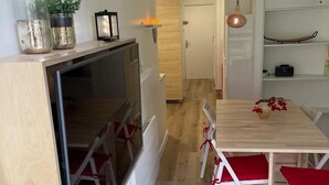 Una cucina moderna con frigorifero integrato, un tavolo da pranzo in legno con sedie rosse e una lampada a sospensione.