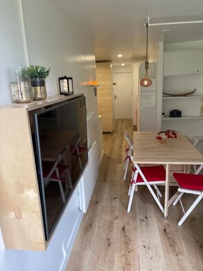 Eine moderne Küche mit einem eingebauten Kühlschrank, einem Holztisch mit roten Stühlen und einer Pendelleuchte.