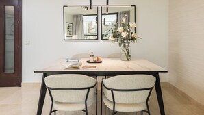 A dining area with a marble table, two chairs, a vase with flowers, and a large mirror above the table. - Constitución III - Two Bedroom Apartment, Sleeps 4 (Malaga)