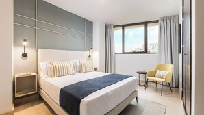 A hotel room with a large bed, bedside tables, a chair, and a window with curtains. - Constitución III - Two Bedroom Apartment, Sleeps 4 (Malaga)