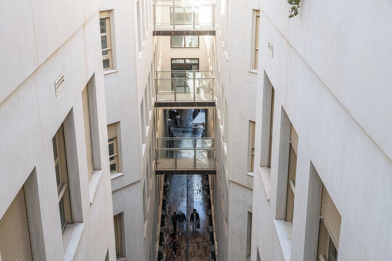 Un interno a più livelli con una scala centrale, ringhiere in vetro e un passaggio stretto.