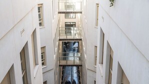A multi-level interior with a central staircase, glass railings, and a narrow passageway. - Constitución III - Two Bedroom Apartment, Sleeps 4 (Malaga)