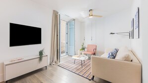Un salon moderne avec un téléviseur à écran plat, un canapé, une table basse et une table d’appoint sur laquelle est posée une plante.