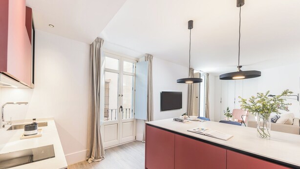 Une cuisine moderne dotée d’un grand îlot central, de luminaires suspendus et d’un téléviseur à écran plat.