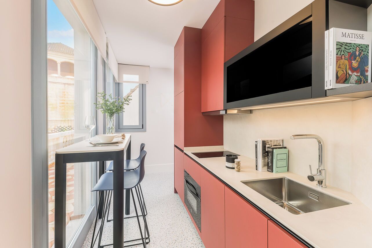 A modern kitchen with a built-in microwave, a stainless steel sink, and a red cabinet.