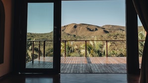 Une pièce dotée d’une grande porte-fenêtre coulissante donnant sur un balcon extérieur avec un plancher en bois et une rambarde en métal.