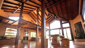 Un intérieur spacieux avec de hauts plafonds, de grandes fenêtres et un plafond en bois rustique.