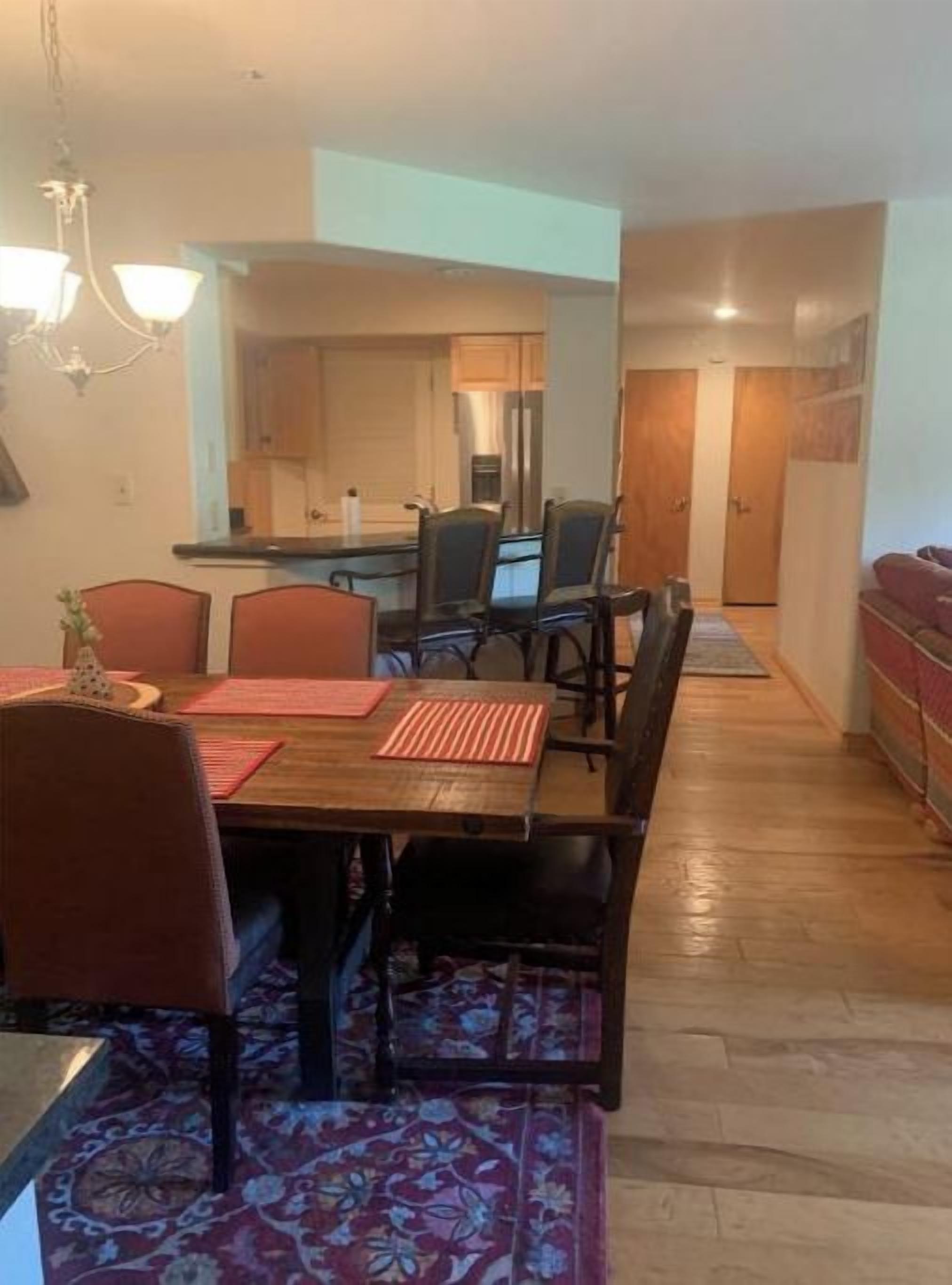 Un coin repas avec une table en bois, des chaises et un lustre.