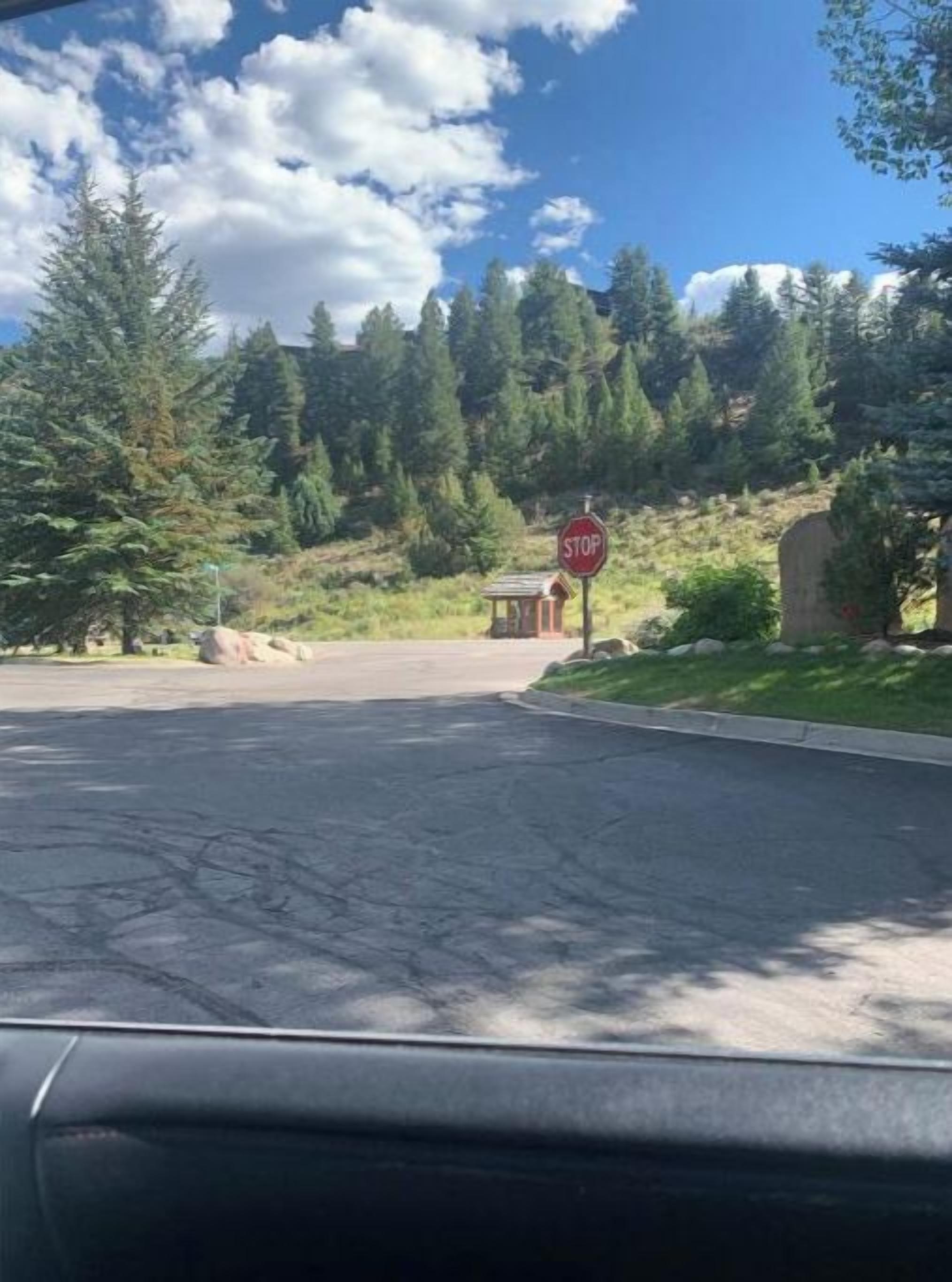 Une route menant à un petit bâtiment où se trouve un panneau de signalisation indiquant un arrêt obligatoire.