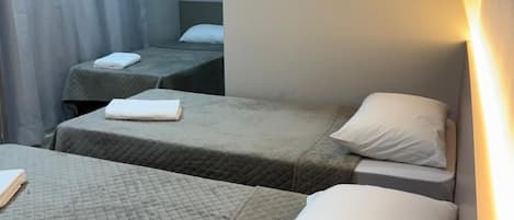 A hotel room with two single beds, each with a quilted bedspread and white pillows.