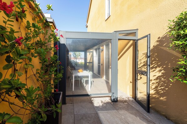 A narrow outdoor patio with a glass door leading to a dining area.