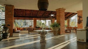Un vestíbulo amplio con una mesa redonda central, pilares de ladrillo y un techo con tejas de terracota.