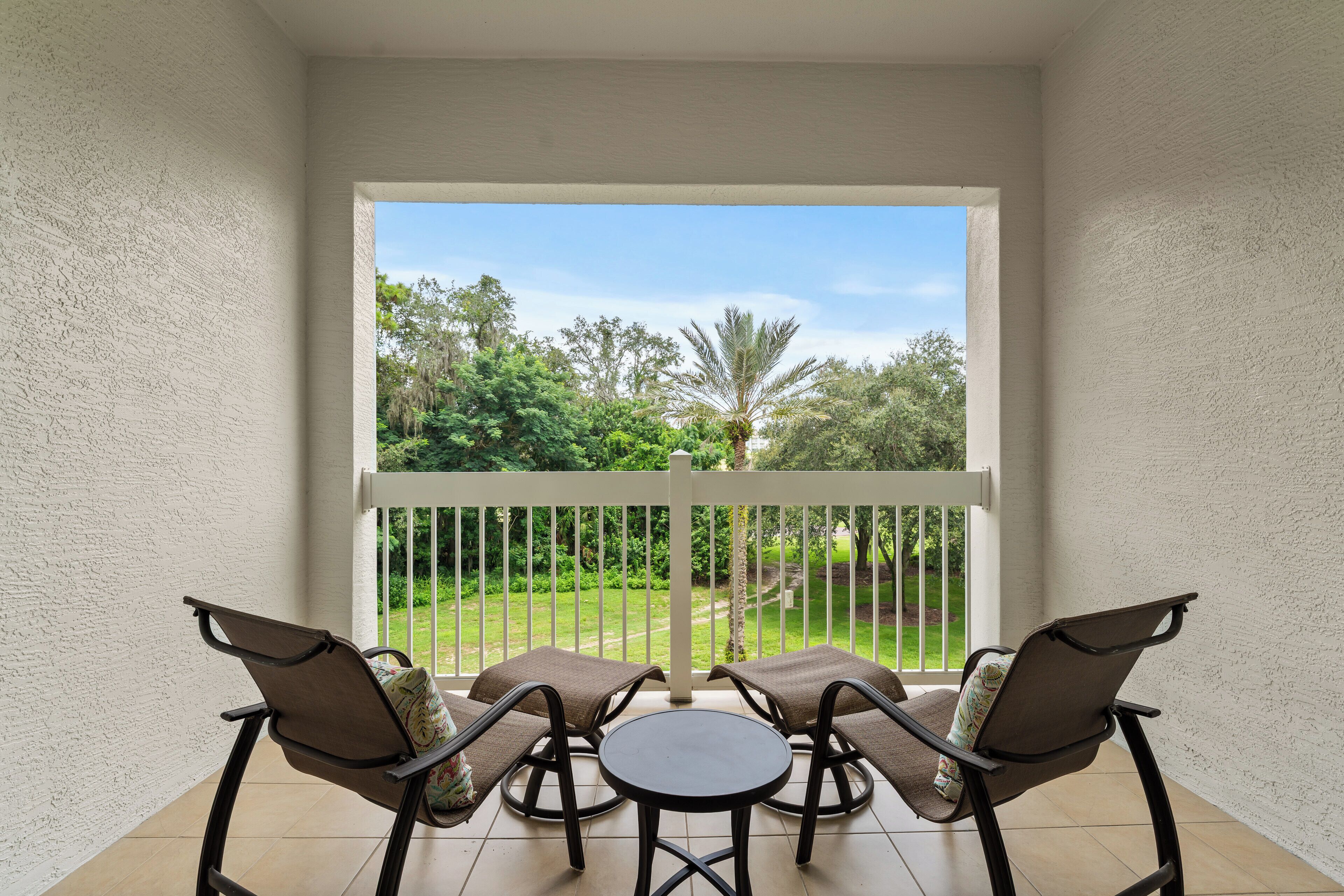 A balcony with a white railing, two chairs, and a small table.