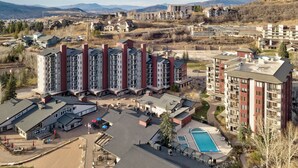 Un hotel de varios pisos con piscina, mobiliario exterior y vistas del paisaje circundante.