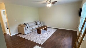A spacious living room with a large sofa, a coffee table, and a ceiling fan. - Spacious 4 Bedroom Retreat Near Lake & Charleston (Moncks Corner)