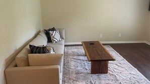 A living room with a beige sofa, patterned cushions, a wooden coffee table, and a patterned rug. - Spacious 4 Bedroom Retreat Near Lake & Charleston (Moncks Corner)