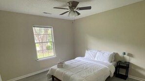 A bedroom with a bed, a ceiling fan, a window, and a nightstand. - Spacious 4 Bedroom Retreat Near Lake & Charleston (Moncks Corner)
