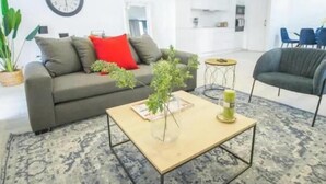 Un salon moderne avec un canapé, une table basse et, au fond, un coin repas.