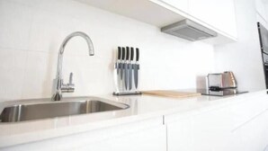 Een moderne keuken met een RVS spoelbak, een messenblok en een broodrooster.