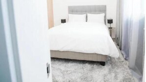 Een slaapkamer met een bed, nachtkastje en een lamp.