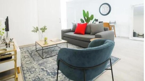 Een moderne woonkamer met een grijze bank, een blauwe fauteuil en een salontafel.