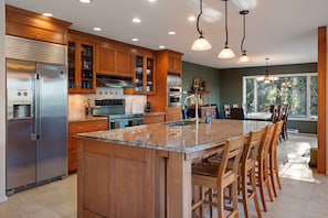 Una cocina moderna con armarios de madera, electrodomésticos de acero inoxidable y una isla grande con taburetes de bar.